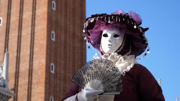 Человек в красочных венецианских костюмах держит китайского фаната на Венецианском карнавале — стоковое видео