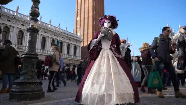 En person i färgglada venetianska kostymer som håller en kinesisk fan i Venedig karneval — Stockvideo