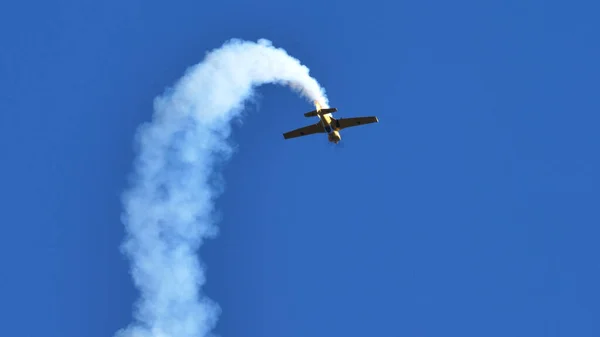 Aerobatic plane loops in the blue sky with white smoke trail. Concept for skills — Stock Photo, Image