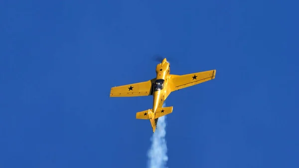 Extreme yellow stunt plane with black stars rises vertically into the blue sky — Stock Photo, Image