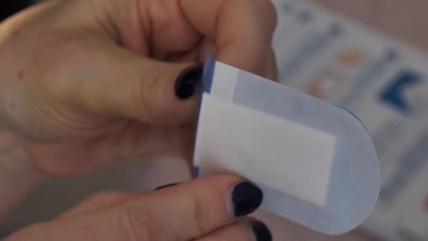 Woman opens a band aid applies to her thumb with a cut - Bandages stitched wound — Stock Video