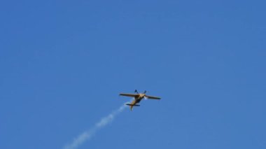 Uçak inanılmaz bir akrobasi gösterisi sergiliyor. Arkasından akrobasi dumanı salıyor.
