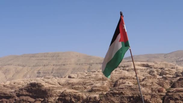 Jordaanse vlag wapperend in de lucht op een zonnige en winderige dag in Petra landschap Jordanië — Stockvideo