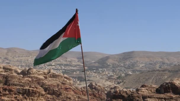 Jordaanse vlag wapperend in de lucht op zonnige en winderige dag in Petra landschap Jordanië — Stockvideo