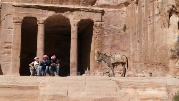 Başında Keffiyeh olan turistler Petra kentindeki bir binanın önünde oturuyorlar. — Stok video