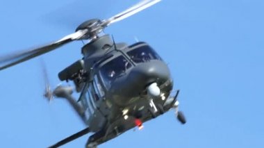 Kurtarma helikopteri havada süzülüyor ve mavi gökyüzündeki dağlara doğru gidiyor.