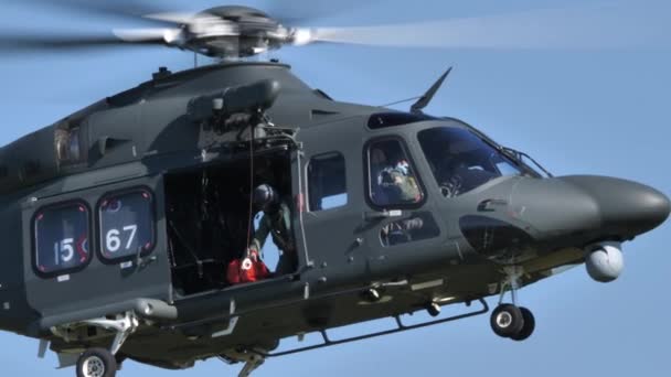 군용 헬리콥터가 윈치에서 들것을 싣고 구조 대원을 내리는 모습 — 비디오