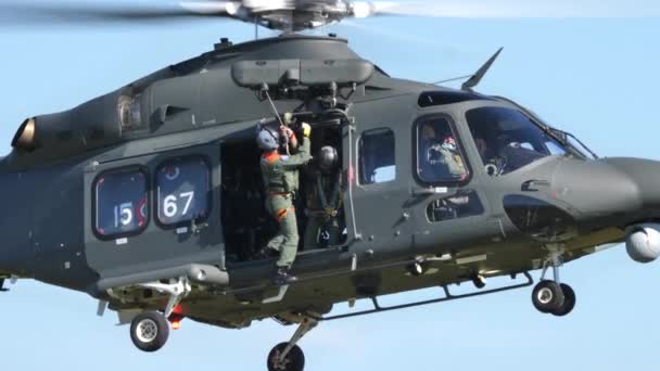 Військовий дослідницький вертоліт опускає рятівника з лебідкою в стаціонарному польоті на малій висоті — стокове відео