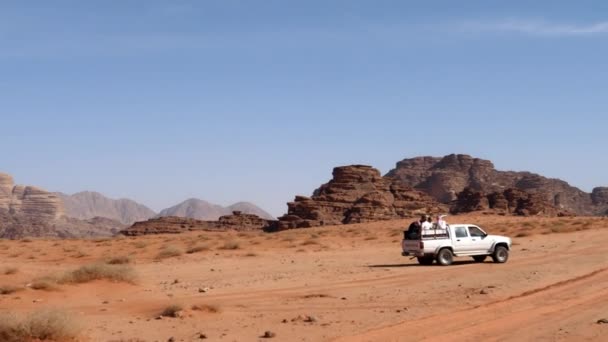 Pojazd terenowy 4x4 biegnie po torach na pustynnym czerwonym piasku z turystami na pokładzie — Wideo stockowe
