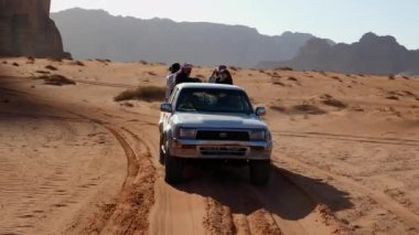 4wd off-road SUv çöl yolunda turistlerle birlikte ilerliyor.