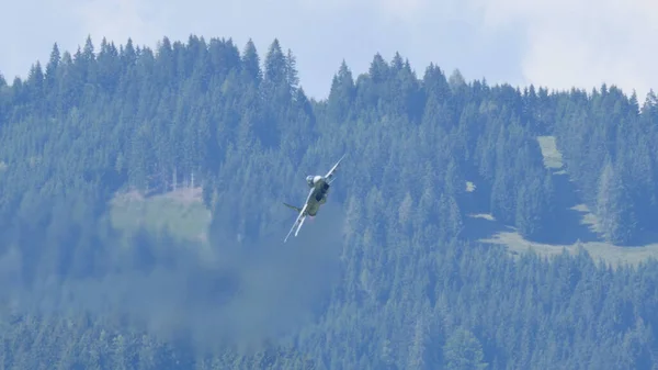 Avion militaire en vol avec forêt verte et fond de montagnes — Photo