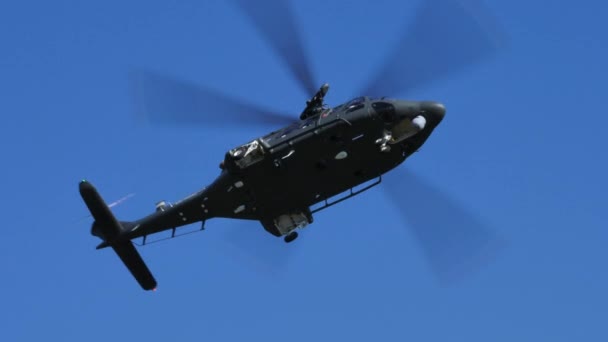 低飛行中の緑のカモフラージュの軍用ヘリコプターは木の後ろに隠れる — ストック動画