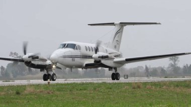Çift motorlu turboprop uçak kalkış için askeri piste iniyor.
