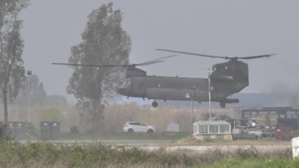 Heavy lift grey helicopter landing on military airport helipad after a mission — Stock Video