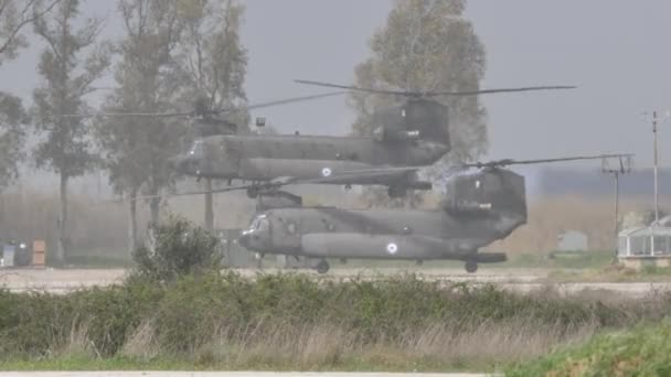 Two grey tandem rotor chopper landing on NATO helipad after a combat mission — Stock Video