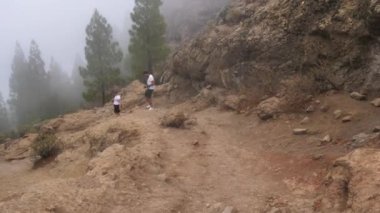 Turistler, İspanya 'nın Gran Kanarya Adası' ndaki Roque Nublo noktasındaki volkanik kayada yürüyüş yapıyorlar.