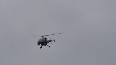 Yeşil kahverengi kamuflaj tarihi askeri helikopter eğitim uçuşunda.