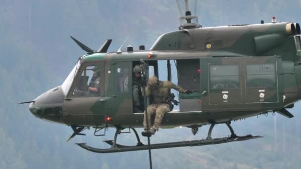 Assault soldiers in combat gear descend from rope tied to a hovering helicopter — Stockvideo
