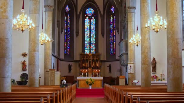 Vaduz Cathedral of St. Florin interior with wooden benches candles chandeliers — Vídeos de Stock