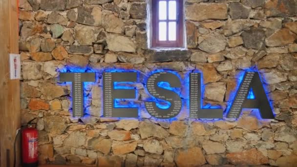 Velké logo Tesla s osvětlením na cihlové zdi uvnitř Památníku Nikoly Tesly — Stock video