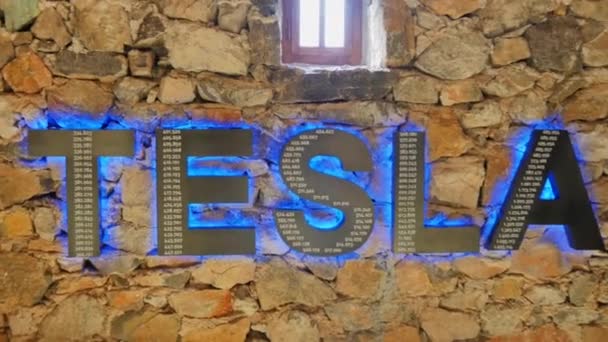 Logo Tesla s modrým osvětlením na cihlové zdi uvnitř památníku Nikoly Tesly — Stock video