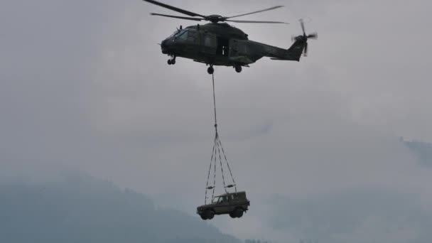 Elicopter militar în zbor cu un vehicul de teren pe cârlig baricentric — Videoclip de stoc