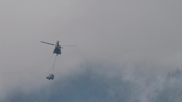 Helikopter vliegend met militair voertuig hangend met een touw aan barycentrische haak — Stockvideo
