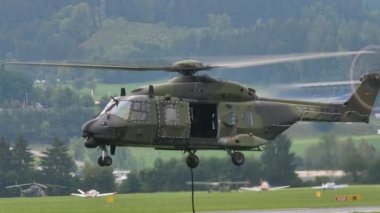 Yeşil kamuflajlı askeri helikopter yan kapağı açık bir çayıra indi.