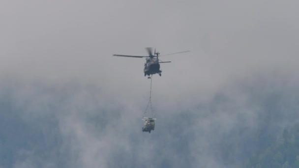 Helicopter in flight carries a load hanging underneath with a rope — ストック動画