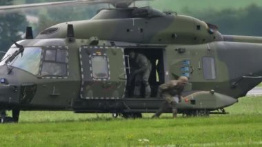 Soldiers exit from a green camouflage military helicopter during a NATO exercise