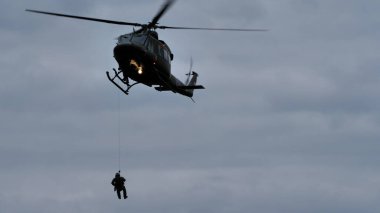 Cerklje ob Krki Slovenya 29 Mayıs 2022 Helicopter sabit uçuşta vinç aşırı kötü hava koşullarıyla kurtarma ekipleri iniyor. Çok yetenekli askeri pilotlar kavramı. Slovenya Hava Kuvvetleri 'nden Bell 412