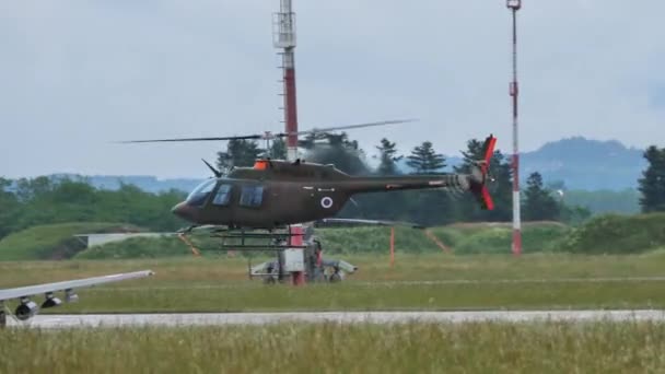 2022年5月29日 一架低空飞行的深绿色小型伪装军用直升机在雨天以森林为背景的机场坠毁 斯洛文尼亚空军贝尔206 — 图库视频影像