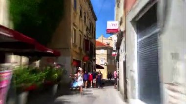 Pula Hırvatistan AUGust, 15, 2020 Hyperlapse, 4K 'da tarihi yolda yürüyor ve şehir meydanında restoran önlerinde yemek yiyen turistlerle son buluyor. Augustus Tapınağı. Büyütme bulanıklık efekti