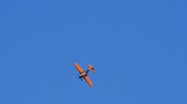 Thiene Italy OCTOBER, 17, 2021 Aerobatic plane performs a four points roll, basic aerobatic maneuver. Sukhoi Su-31 in black and orange colors is a Russian famous extreme aerobatics plane