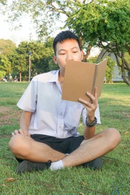 Taylandlı çocuğu kapatın ve doğa bahçesinde kitap okuyun.