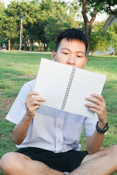 Taylandlı çocuğu kapatın ve doğa bahçesinde kitap okuyun.