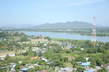 Tayland 'ın Kanchanaburi bölgesindeki köy, nehir ve dağın manzarasını görmek için dağdaki tapınağa bakın.