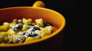 Etli ve peynirli patates dolu sarı seramik güveç. Siyah bir arkaplana yerleştir. Foodie. Yakın görünüm