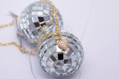 Noel topunda elmas kolye desenli beyaz arka planda duruyor.