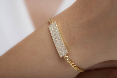 Beyaz elbiseli genç bir kadın elmas bilezik takıyor..