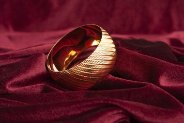 Burgundy kadife kumaş üzerinde altın bilezik