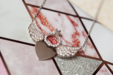 Siyah arka planda melek kanatları olan gümüş kolye.