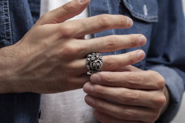 Beyaz tişörtlü, mavi kot gömlekli, gümüş yüzüklü genç bir manken..