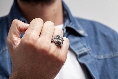 Beyaz tişörtlü, mavi kot gömlekli, gümüş yüzüklü genç bir manken..