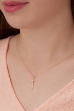 Pembe elbiseli kıza yakın plan ince zirkon çapraz kolye. E-ticaret satışları için kolye fotoğrafı.