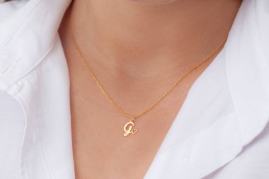 Çekici beyaz elbiseli kızın boynunda altın rengi bir kolye. Kişisel kolye imajı. E- ticaret için mücevher fotoğrafı, online satış, sosyal medya.