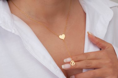 Çekici beyaz elbiseli kızın boynunda altın rengi bir kolye. Kişisel kolye imajı. E- ticaret için mücevher fotoğrafı, online satış, sosyal medya.