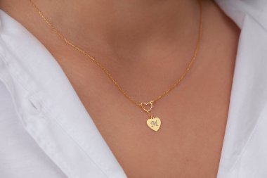 Çekici beyaz elbiseli kızın boynunda altın rengi bir kolye. Kişisel kolye imajı. E- ticaret için mücevher fotoğrafı, online satış, sosyal medya.