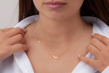 Çekici beyaz elbiseli kızın boynunda altın rengi bir kolye. Kişisel kolye imajı. E- ticaret için mücevher fotoğrafı, online satış, sosyal medya.