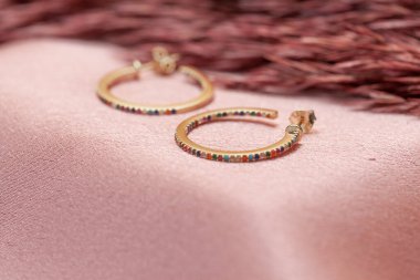 Pembe arka planda küpe resmi. Mücevher yaratıcı ve renkli bir arka planda sergileniyor. E- ticaret için mücevher fotoğrafı, online satış, sosyal medya.